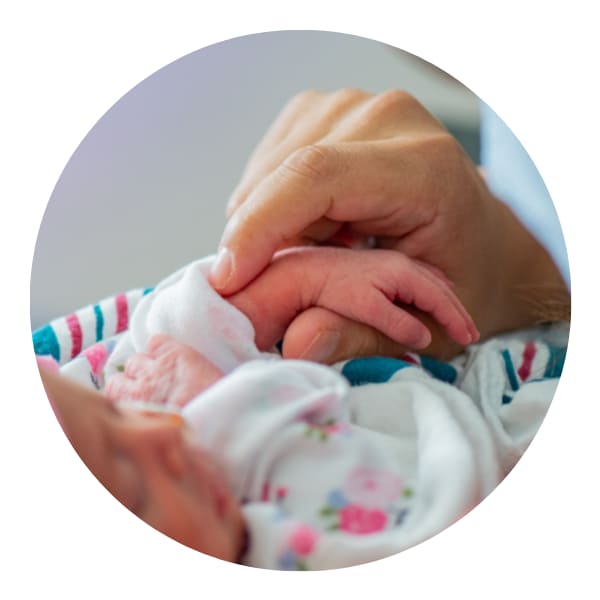 adult hand holding the arm of a tiny infant